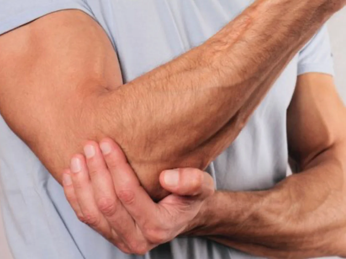 Łokieć tenisisty mężczyzna trzyma się za bolący łokieć